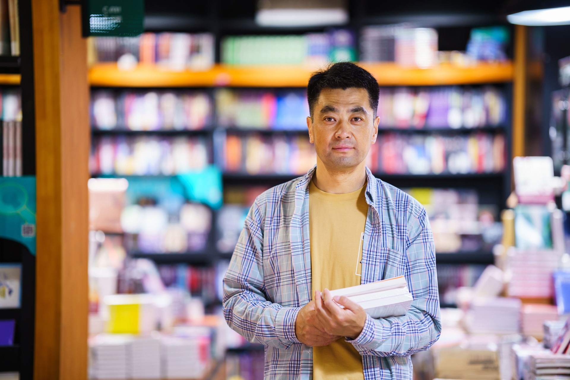 Asian middle-aged man borrowing books at city public library